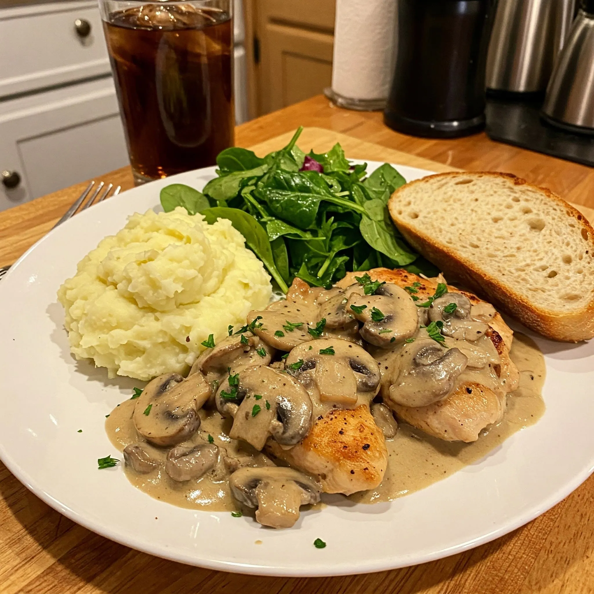 Creamy mushroom chicken served with mashed potatoes, a fresh salad, and crusty bread in a cozy kitchen setting.