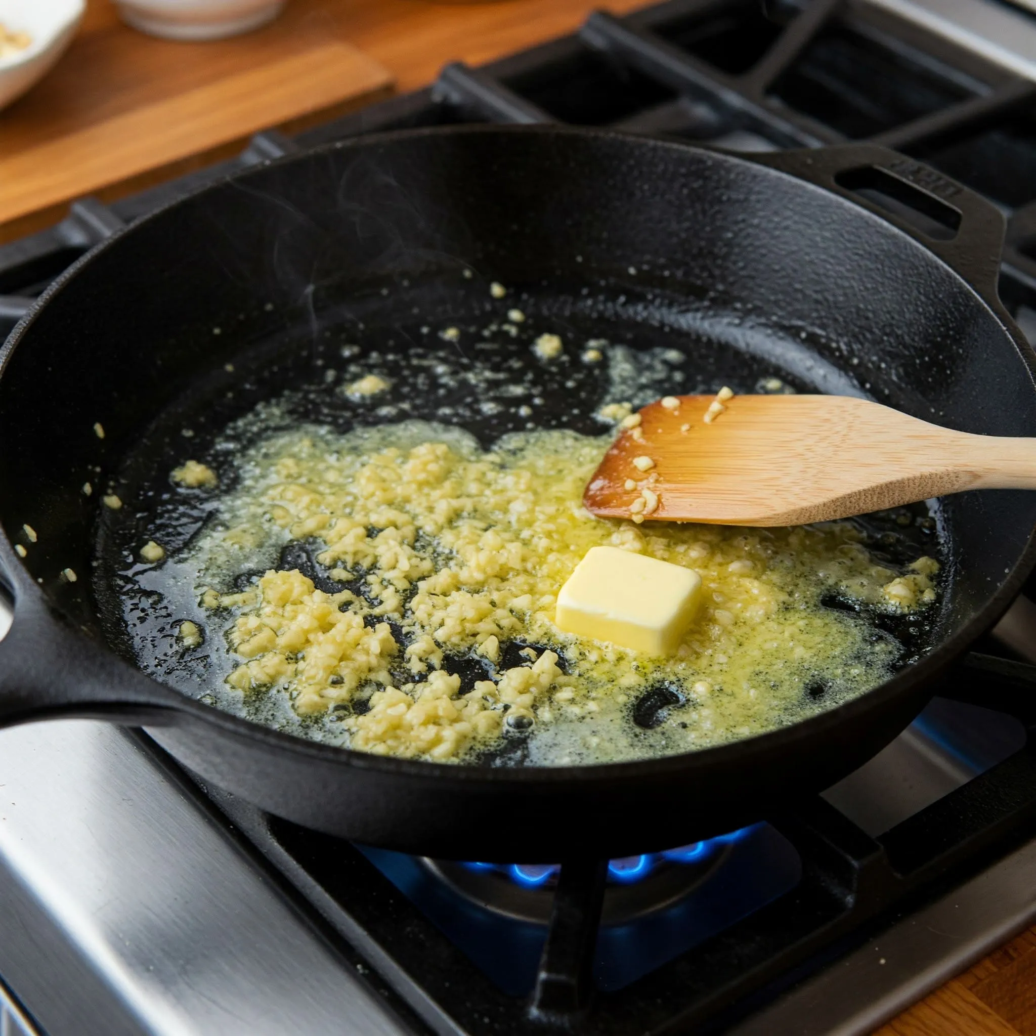 Skillet with melted butter and minced garlic sizzling, ready to make Alfredo sauce.