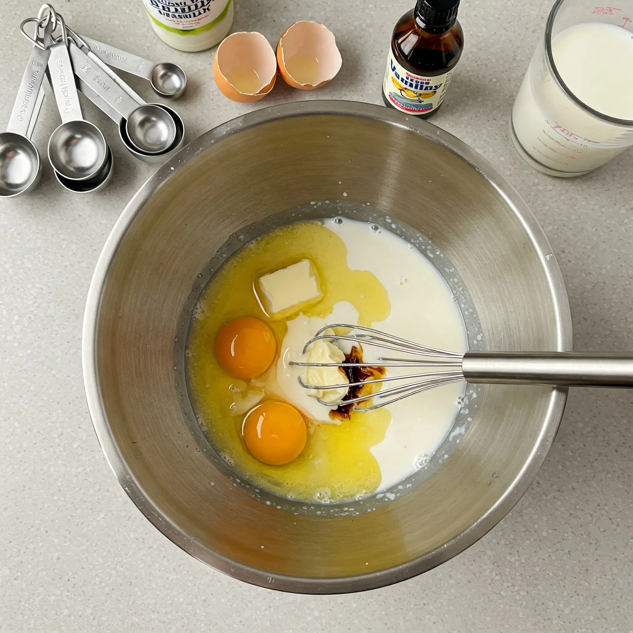 Mixing wet ingredients for a birthday cake, including eggs, melted butter, vanilla extract, and milk, in a kitchen.