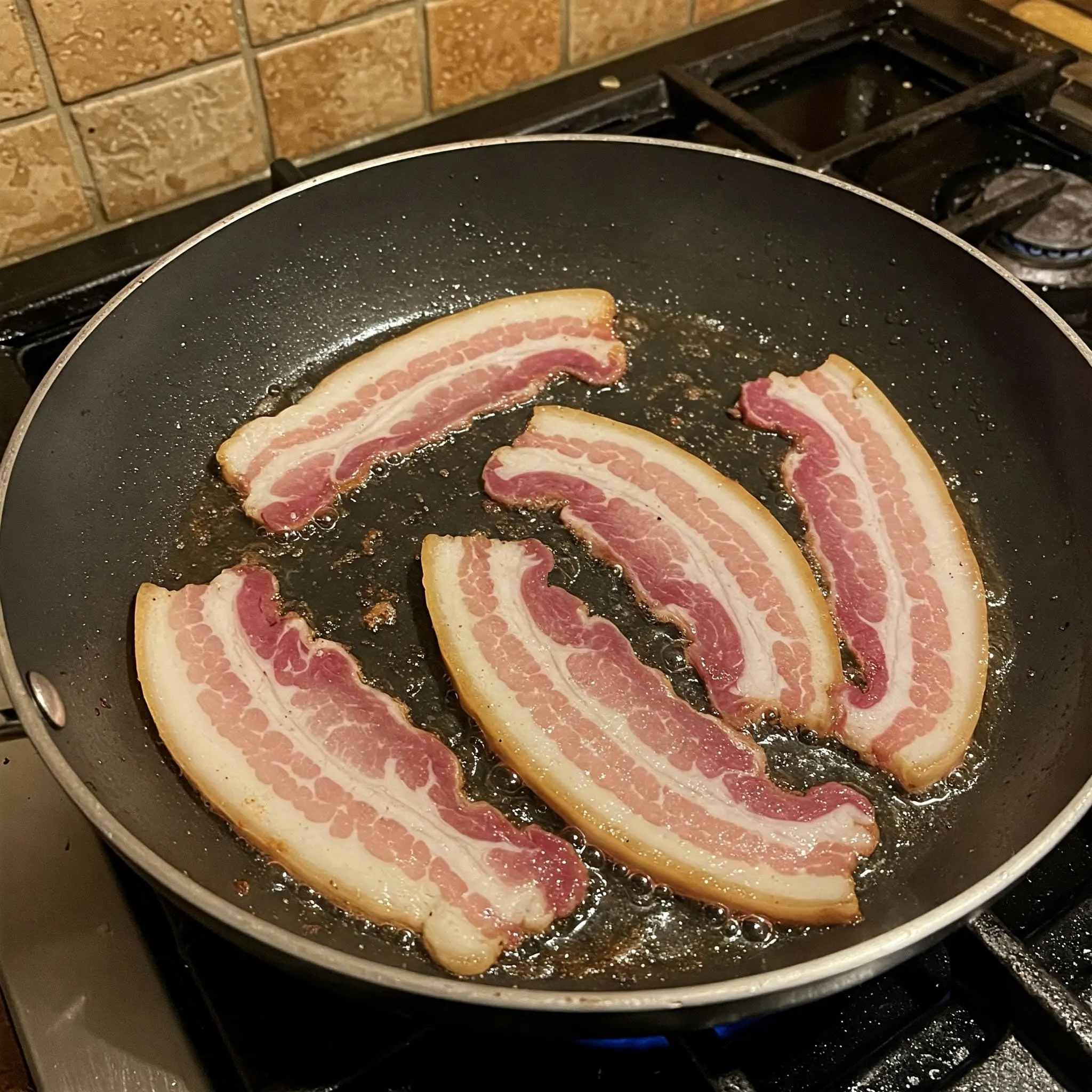 Chef cooking guanciale in a pan for Carbonara recipe.