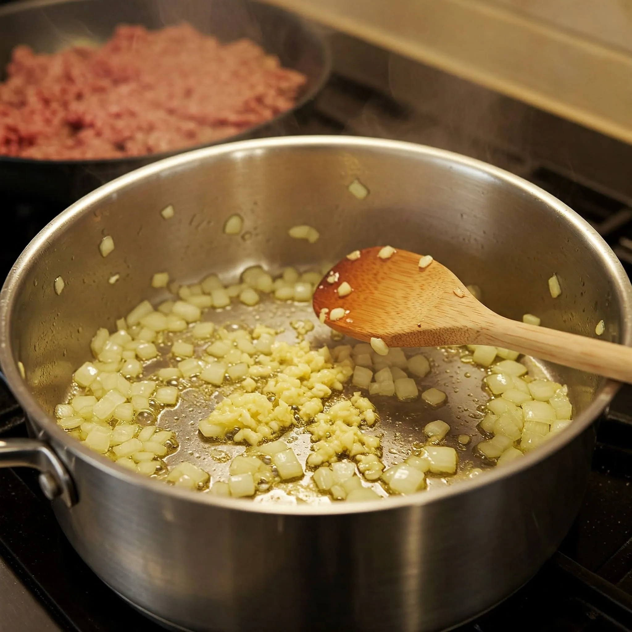 Sautéing onions, garlic, and ground beef in a pot on the stove.